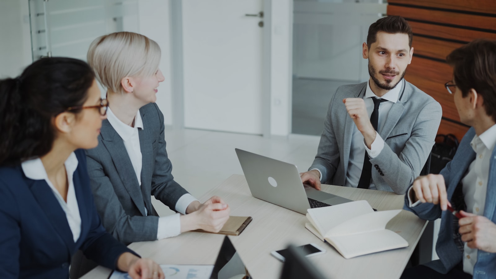 Four professionals in a business meeting around a table, representing a fractional executive leading a strategy session