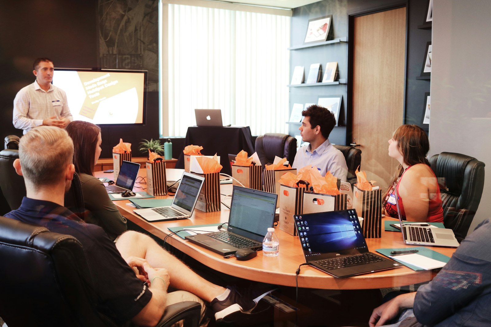 A leader standing to present to a seated team during a work meeting, discussing strategy