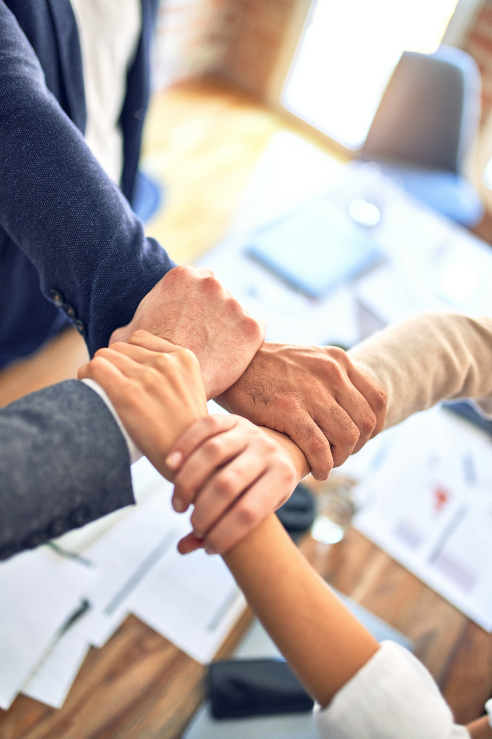 Colleagues clasping wrists in a gesture of unity and trust, representing psychological safety at work