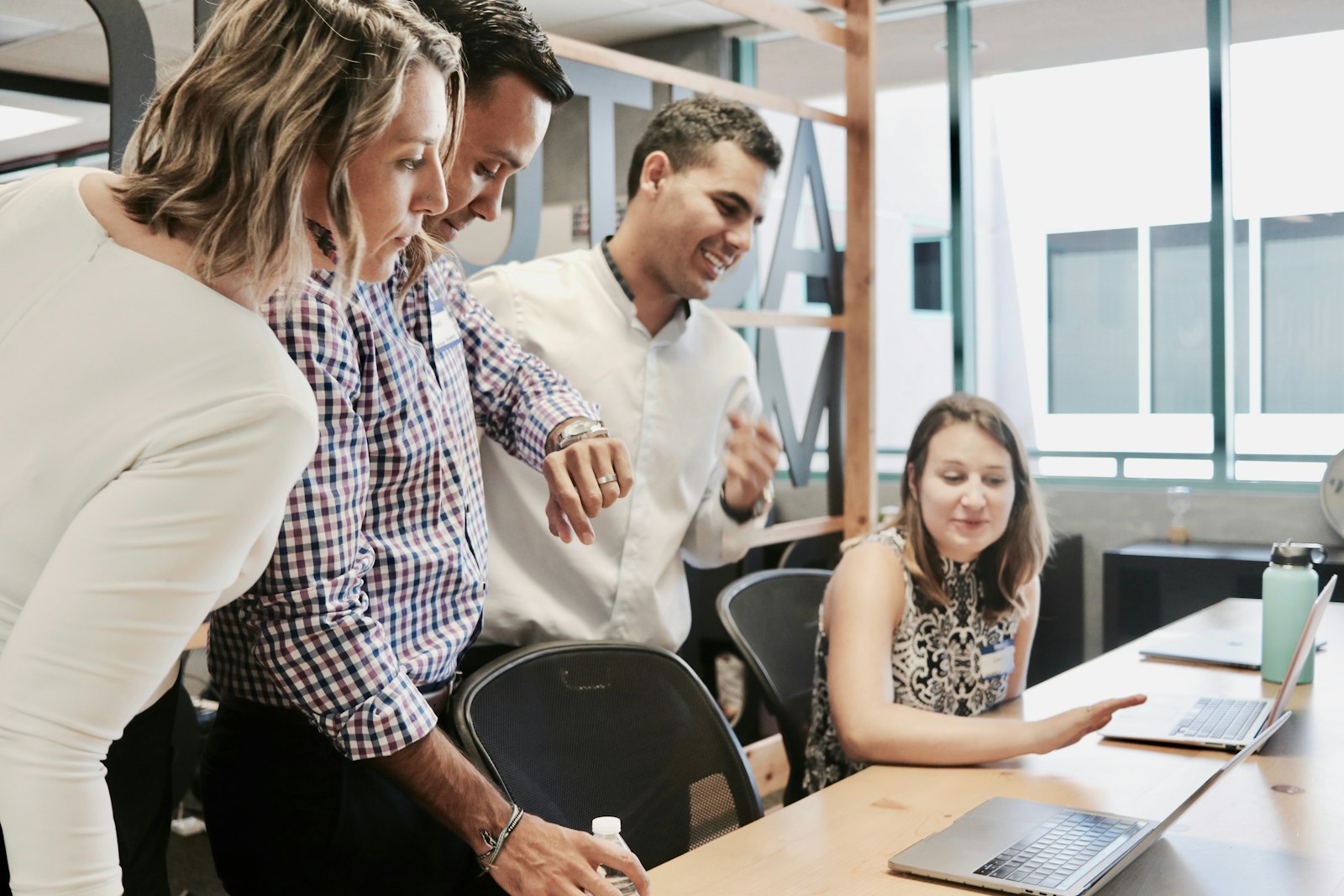 A small team gathered around a desk mentoring a colleague on a project, building capability from within